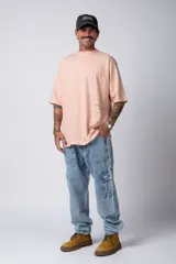 Remera blanca de corte oversize con cuello redondo y mangas cortas. Presenta un pequeño estampado tipográfico en la parte inferior frontal y un diseño gráfico de mayor tamaño en la espalda.