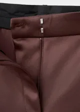 Pantalón largo de tiro medio en tejido satinado color marrón, con diseño de pernera recta, trabillas para cinturón, pinzas delanteras, bolsillos laterales y bolsillos de ribete en la parte posterior. Cierre frontal oculto con botón, gancho y cremallera.