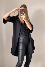 Camisa negra de tejido suave tipo seda, con manga tres cuartos y volados irregulares en mangas y ruedo.