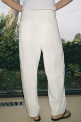 Pantalón de tiro medio confeccionado en una mezcla de lino y algodón. Presenta un diseño de corte recto con trabillas en la cintura, bolsillos laterales y cierre frontal con cremallera, botón y ganchos metálicos.