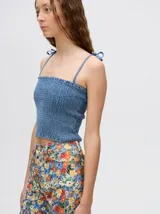 Top corto de tela fruncida color celeste, con tirantes finos que se atan en los hombros.