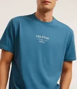 Remera celeste de algodón con cuello redondo y mangas cortas. Estampa frontal con la palabra "VELEJAR" y otros textos en blanco.
