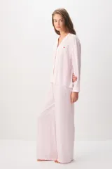 Pijama rosado de 100% viscosa con diseño a rayas sutiles, compuesto por una camisa de manga larga con cuello solapa y botones delanteros, y un pantalón largo de corte holgado con cintura elástica y cordón ajustable. Presenta un pequeño detalle bordado de corazón rojo en el pecho de la camisa.