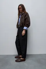 Pantalón marrón de tiro alto y silueta amplia, confeccionado con pinzas en el frente y bolsillos laterales.