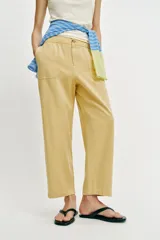 Pantalón de tiro medio color amarillo, con cintura elástica, bolsillos de plastrón en el delantero y pernera holgada que se estrecha hacia el tobillo. Cuenta con cierre frontal de cremallera y botón.