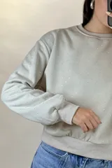 Buzo de cuello redondo y manga larga, color negro, con diseño de pequeños puntos brillantes distribuidos por toda la prenda. Presenta puños y ruedo acanalados.