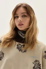 Sweater de punto color bordó con diseño de flores estampadas en tono crema, cuello redondo y puños con detalle de franjas en contraste. Presenta un bordado pequeño en el pecho.