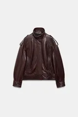 Chaqueta tipo bomber de piel 100% color bordó, con cuello alto, manga larga con trabillas y hombros con trabillas. Tiene bolsillos delanteros y cierre frontal con cremallera y botones ocultos por solapa.