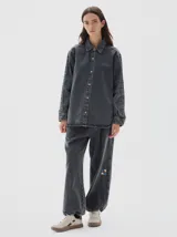Camisa de denim de corte recto y estilo clásico, confeccionada en tejido de algodón con acabado lavado. Presenta cuello camisero, cierre frontal con botones metálicos y mangas largas con puños abotonados.