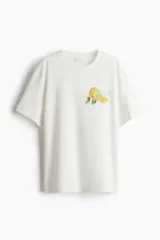 Remera de corte holgado confeccionada en punto de algodón, con cuello redondo y diseño estampado de limones con la frase 'aroma di limoni' en el pecho.