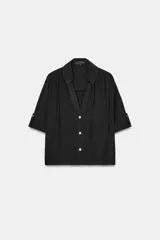 Camisa de cuello solapa y escote pico, color verde militar, con manga corta con trabilla y botón, y cierre frontal con botones.