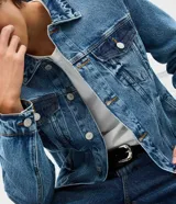 Campera de jean azul para hombre, con efecto desteñido, cuello inglés, cierre frontal de botones metálicos y bolsillos frontales con solapa.