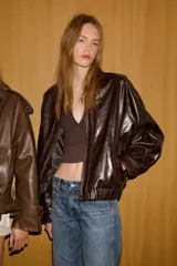 Chaqueta bomber de estilo oversize confeccionada en material efecto piel con acabado brillante. Presenta cuello redondo, cierre frontal con cremallera metálica, bolsillos laterales de vivo y bajo con elástico.