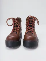 Botas de cuero estilo trekking, en combinación de colores verde, marrón y gris, con plataforma de goma negra, cordones bicolor inspirados en cuerdas de escalada y pasadores en tono rojizo.
