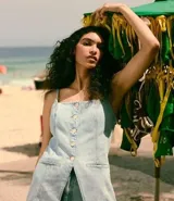 Chaleco largo de jean con escote recto, breteles finos ajustables y cierre frontal con botones. Presenta un corte acinturado con pences, bolsillos delanteros decorativos y ruedo en punta.