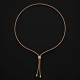 Collar tipo lazo con cordón de cuero sintético en tono beige y detalle central deslizante metálico con baño de oro 18k y circonias.