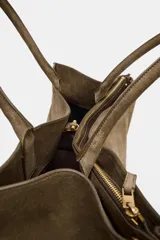 Bolso de hombro formato maxi city confeccionado en piel de gamuza color marrón. Cuenta con doble asa de hombro, doble compartimento interior y cierre mediante clip metálico y cremallera.