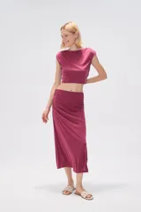 Falda midi de corte tubo confeccionada en modal, con detalle de frunces laterales que aportan movimiento y ajuste al cuerpo.