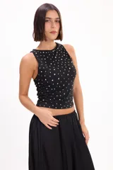 Top halter negro ajustado al cuerpo, con aplicaciones de tachas metálicas plateadas distribuidas por toda la prenda.