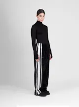 Pantalón de terciopelo negro de corte ancho, con cintura elástica y tres rayas blancas verticales en los laterales.