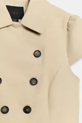 Chaqueta entallada color beige con cuello solapa, manga corta abullonada y doble botonadura frontal.