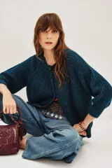 Cardigan de punto grueso acanalado color azul, con cuello redondo, cierre frontal de botones y mangas largas.