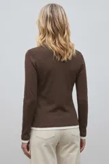 Remera de manga larga con diseño de efecto superpuesto, cuello en V y puños en color blanco contrastante.