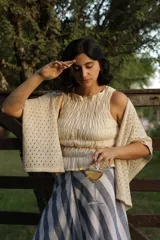 Ruana de tejido artesanal en color crudo, con diseño de calados geométricos y terminación de borde recto.