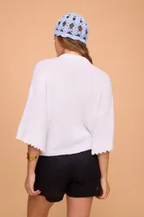 Saco tejido a máquina en lino y algodón color celeste, con silueta en línea A, mangas anchas, escote redondo con bordado en la delantera y botones de nácar. Largo por arriba de la cola.