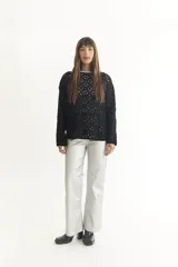 Sweater negro de tejido crochet con mangas largas y cuello redondo.