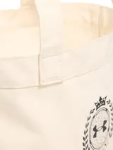 Bolso tote de lona color crema con logo Under Armour Athletics estampado en negro.