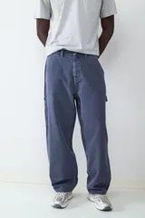 Pantalón estilo carpintero de corte holgado, color azul marino con efecto lavado. Presenta bolsillos laterales funcionales, cierre frontal con botón y costuras reforzadas.