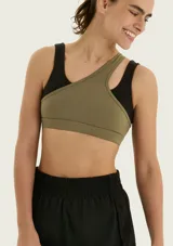 Top deportivo asimétrico de color verde militar, con diseño de un solo hombro y doble tirante cruzado.