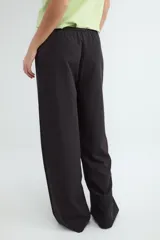 Pantalón negro de corte wide leg, con cintura elástica ajustable mediante cordón y bolsillos frontales.