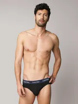 Pack de tres slips Calvin Klein de color negro, confeccionados en mezcla de algodón y elastano. Cuentan con talle medio y una distintiva cintura elástica con logo de la marca en colores azul marino, blanco y verde.