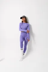 Conjunto deportivo de dos piezas color lila, compuesto por un top de manga larga con diseño seamless y calzas de tiro alto con detalles texturizados en los laterales.