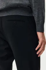 Pantalón de vestir negro de corte slim fit, con cierre de botón, bolsillos laterales y bolsillos traseros ribeteados con botón.
