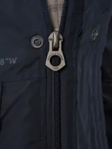 Campera de abrigo azul marino con capucha, cierre frontal con botones y cremallera, múltiples bolsillos y forro interior naranja.