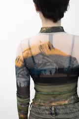 Remera crop top de mangas largas y cuello alto, confeccionada en tejido de red transparente con estampado de paisaje montañoso.