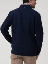 Buzo de hombre con cierre frontal completo y tapeta, cuello alto con terminación en contraste, manga larga y bolsillos laterales. Confeccionado en tejido de algodón orgánico y poliéster reciclado.
