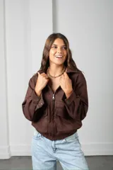 Campera corta de gamuza color marrón, con cierre frontal, cuello camisero y bolsillos frontales con solapa.