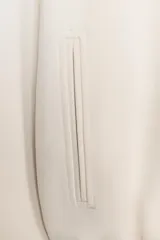 Chaqueta de corte corto y diseño abullonado en color marrón oscuro, con cuello solapa, mangas largas con puños elásticos y cierre frontal con cremallera metálica. Cuenta con bolsillos delanteros de doble vivo.
