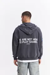 Campera con capucha de algodón con efecto acid wash, corte oversize y estampa gráfica en la espalda con la frase 'WE ARE NOT HERE TO PLAY GAMES' y logo de la marca Mistral.