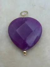 Dije de corazón grande de piedra facetada en colores negro, violeta y naranja, con engarce dorado.