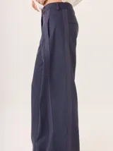 Pantalon de pierna ancha color azul marino, con costuras decorativas en contraste de color rojo y franjas laterales a tono. Cuenta con cintura alta, cierre frontal y bolsillos laterales.