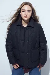 Campera acolchada de color negro con diseño capitoneado, cierre frontal con botones y cuello clásico.