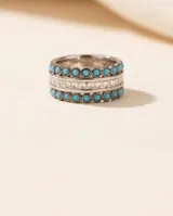 Anillo ancho de plata 925 con hileras de pequeñas piedras turquesas redondas y una línea central de piedras blancas cuadradas facetadas.