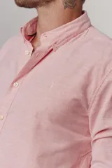 Camisa de hombre color crema, de corte clásico, con cuello abotonado y mangas largas.