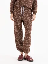 Pantalón jogging marrón con estampado de labios, cintura elástica con cordón ajustable y puños en los tobillos.