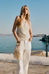 Top blanco con lentejuelas plateadas, de cuello halter y espalda descubierta.